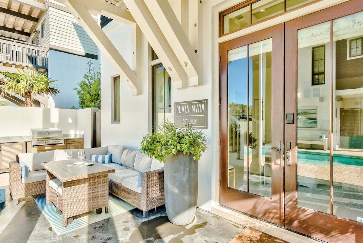 A modern outdoor living area with a wicker sofa, a wooden table, and a large planter.