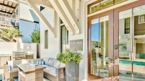 A modern outdoor living area with a wicker sofa, a wooden table, and a large planter.