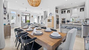 A spacious dining area with a wooden table set for a meal, surrounded by modern chairs.