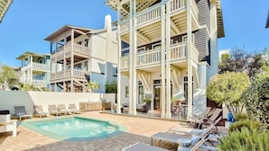 A pool area with lounge chairs and a building with multiple balconies.