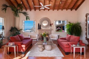 A living room with two red sofas, a glass coffee table, a fireplace, and a ceiling fan.