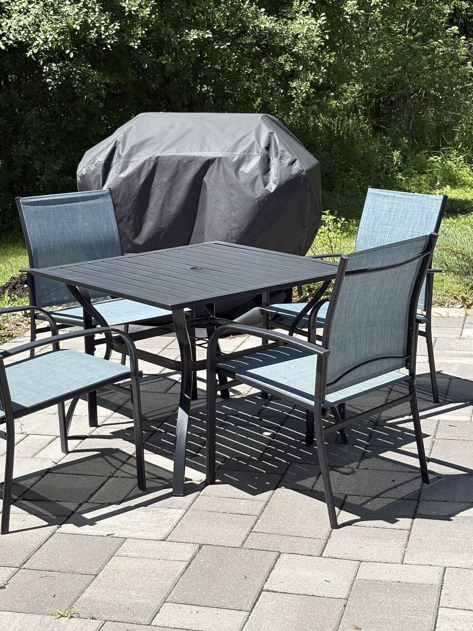 Un patio al aire libre con una mesa y sillas, cubierto por un toldo grande y oscuro.