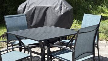 Un patio al aire libre con una mesa y sillas, cubierto por un toldo grande y oscuro.