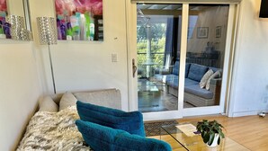 A living room with a sofa, teal cushions, a fluffy rug, a glass coffee table, and a potted plant. - Luxury Modern Unit on Market St - w/Private Patio - Hot tub, Fire Pit, Lounge + (SF)