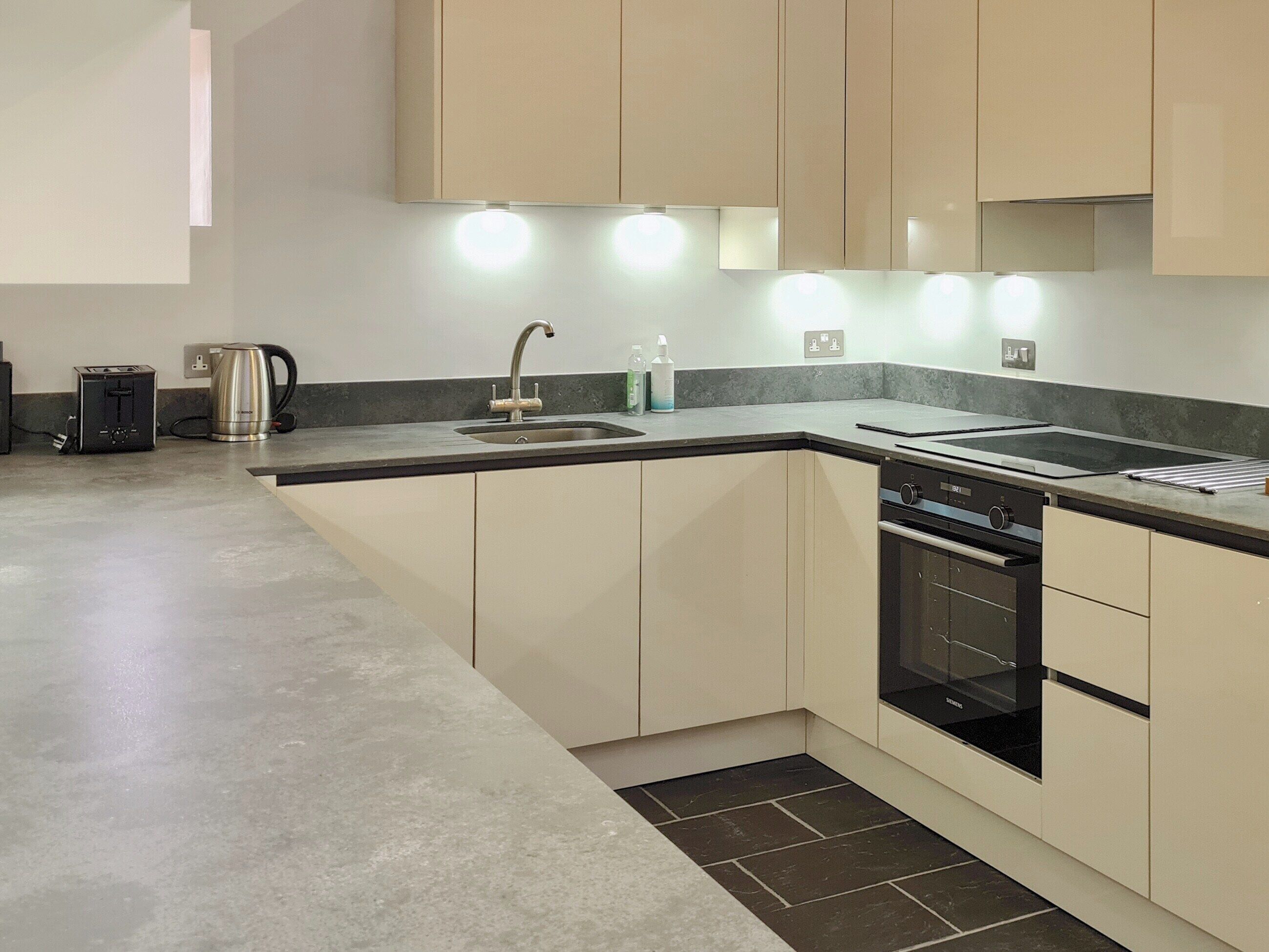 A modern kitchen with a built-in oven, a sink, and a kettle.
