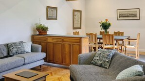 Una sala de estar acogedora con un sofá, una mesa de centro y un comedor con sillas y una mesa de madera.