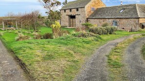 Una casa de campo de piedra con techo inclinado, una puerta de madera y un pequeño porche.
