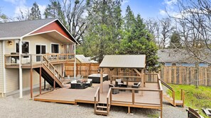 A two-story house with a deck, outdoor seating area, and a hot tub. - Drift Away - A beautiful River front home in Southern Oregon (Gold Hill)