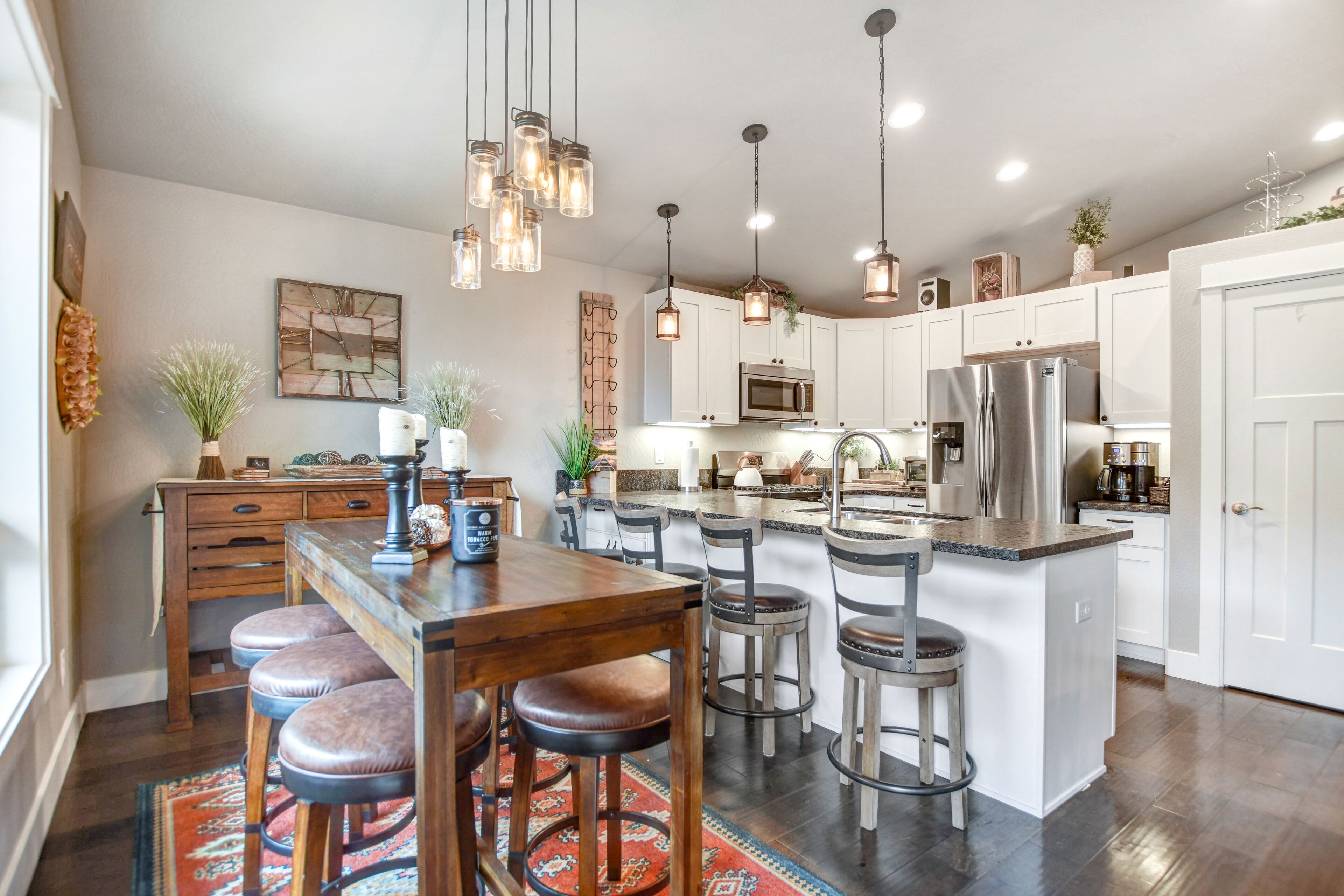 Una cocina moderna con gabinetes blancos, electrodomésticos de acero inoxidable y una isla central con taburetes de bar.