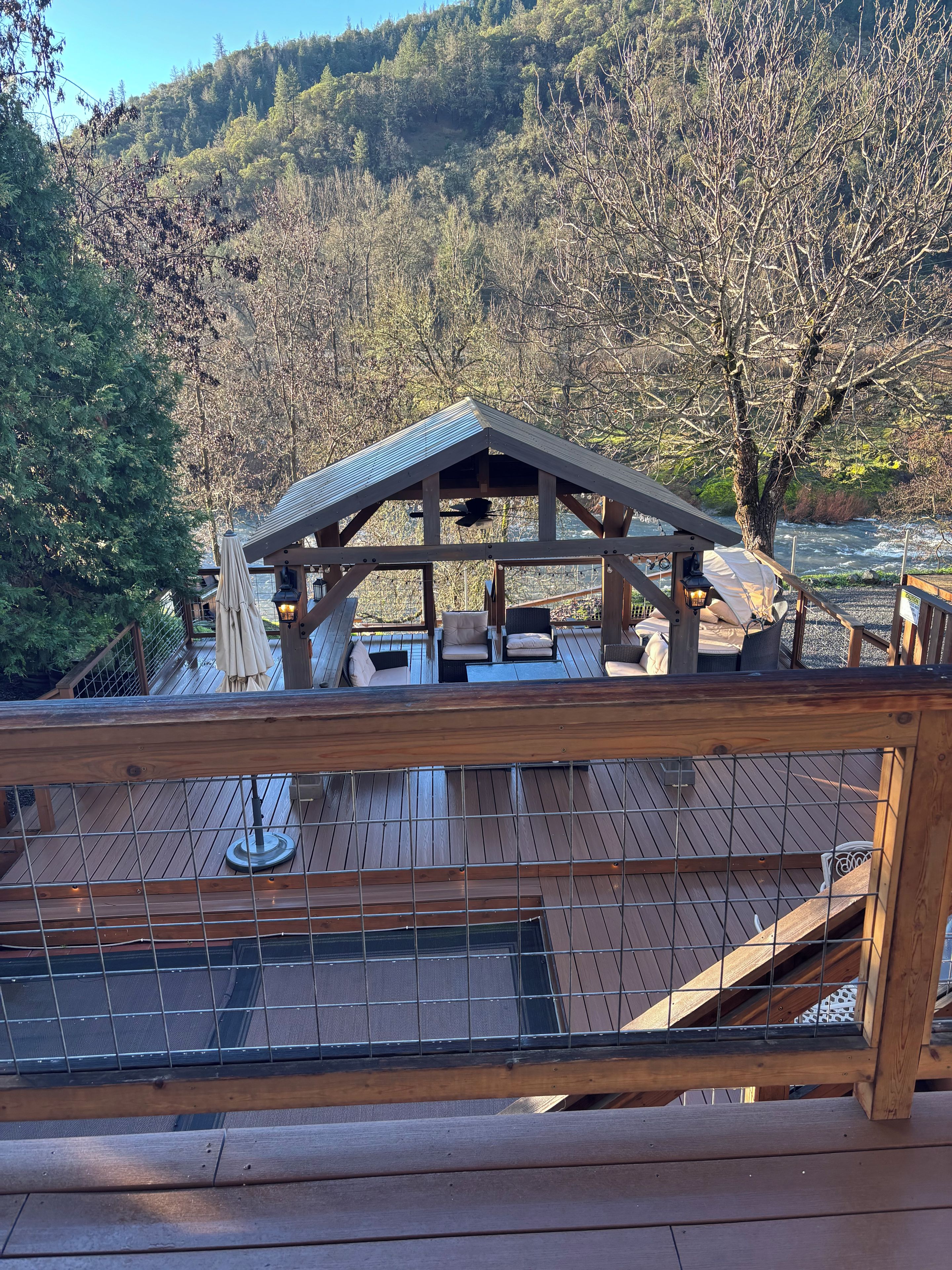 A wooden deck with a covered seating area overlooking a forested hillside.