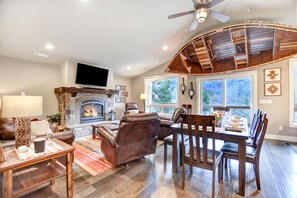 A spacious living room with a fireplace, leather furniture, and large windows. - Drift Away - A beautiful River front home in Southern Oregon (Gold Hill)