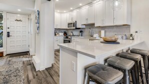 A modern kitchen with white cabinets, a large island with stools, and a hanging light fixture. - 🏔️Ski-In, Ski-Out~Hot Tub~Top Floor~Interlude 301🏔️ (Snowmass Village)
