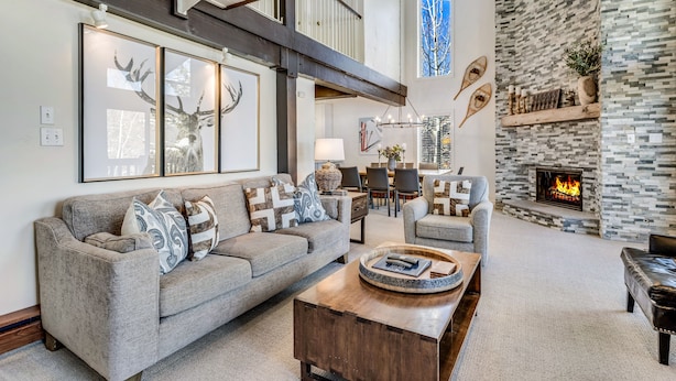 A spacious living room with a gray sofa, a wooden coffee table, and a stone fireplace. - 🏔️Ski-In, Ski-Out~Hot Tub~Top Floor~Interlude 301🏔️ (Snowmass Village)