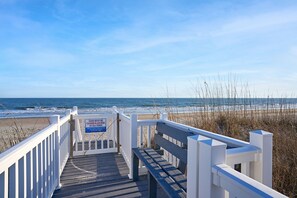 A wooden boardwalk leading to a beach with a sign indicating the gate must be closed and locked at all times.
