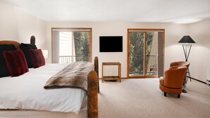 A bedroom with a bed, a TV, a chair, and a lamp. - Casa Del Sol (Vail)