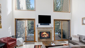 A modern living room with a fireplace, leather furniture, and large windows. - Casa Del Sol (Vail)