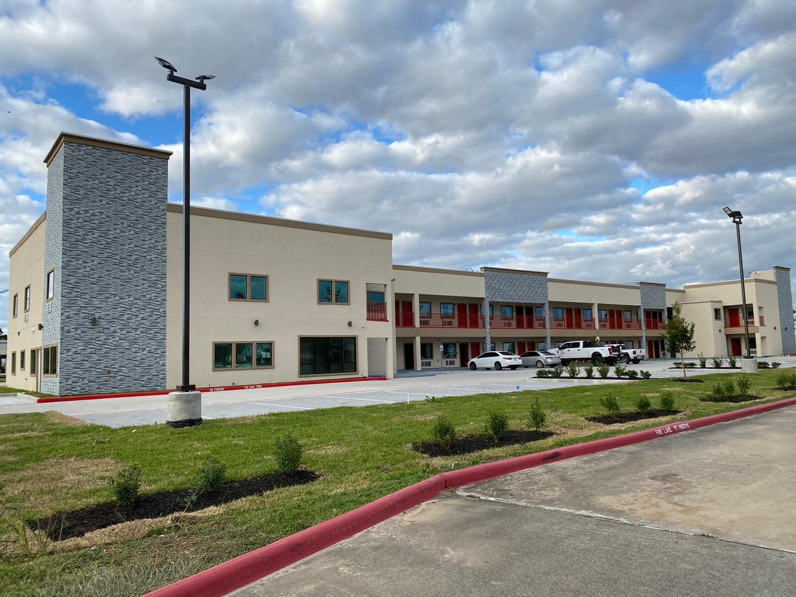 A modern hotel with a flat roof, multiple windows, and a parking lot.