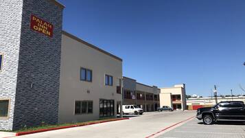 Stylish hotel building with a flat roof and symmetrical facade, featuring multiple windows and a parking area.