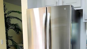 A stainless steel refrigerator in a kitchen with white cabinets and a wooden floor. - SABTR- 710- 6 MIN. WALK TO THE BEACH! POOL, CLEAN,2BR,2BA VILLA, 5-STAR REVIEWS! (St. Augustine)