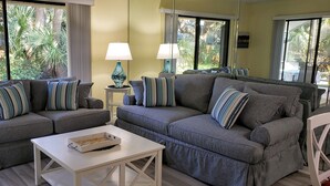 A living room with two grey sofas, striped cushions, a white coffee table, and two lamps. - SABTR- 710- 6 MIN. WALK TO THE BEACH! POOL, CLEAN,2BR,2BA VILLA, 5-STAR REVIEWS! (St. Augustine)