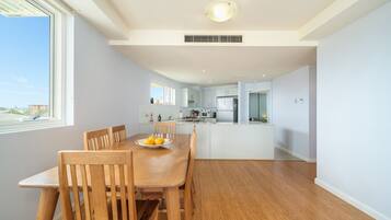 A modern kitchen with white cabinets, a central island, and a dining area with wooden chairs and a table.