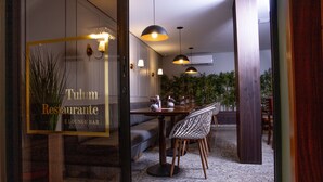 L’intérieur d’un restaurant au design moderne, avec un espace repas comprenant des tables et des chaises, un éclairage suspendu et une enseigne bien visible indiquant « Tulum Restaurante E LOUNGE BAR ».
