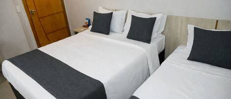 A hotel room with two single beds, a wooden wardrobe, and a small table with a remote control.