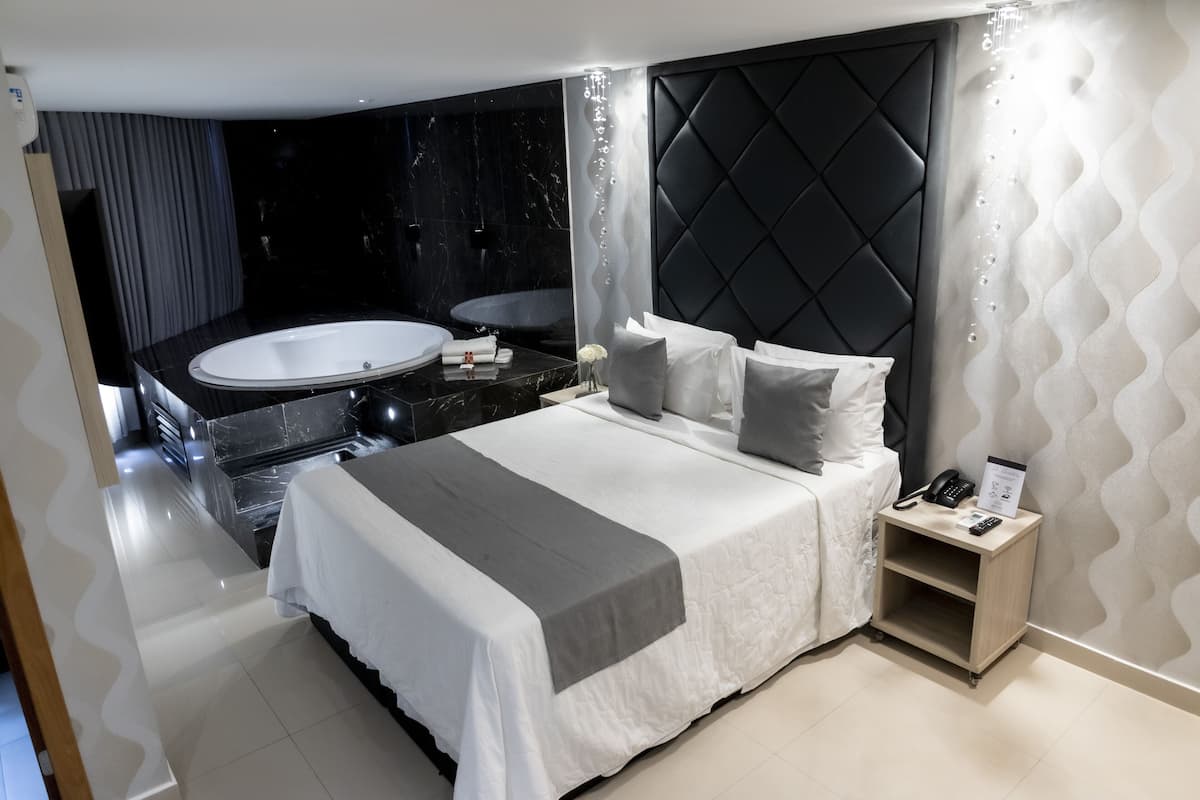 Ein modernes Hotelzimmer mit einem großen Bett, einem eigenen Badezimmer mit Badewanne und einem kleinen Nachttisch mit Telefon und Schild.