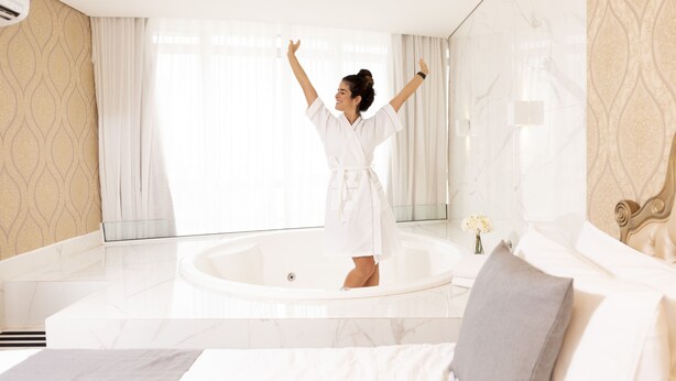 Une salle de bain spacieuse avec une grande baignoire, un lit avec du linge de maison blanc et un design moderne.
