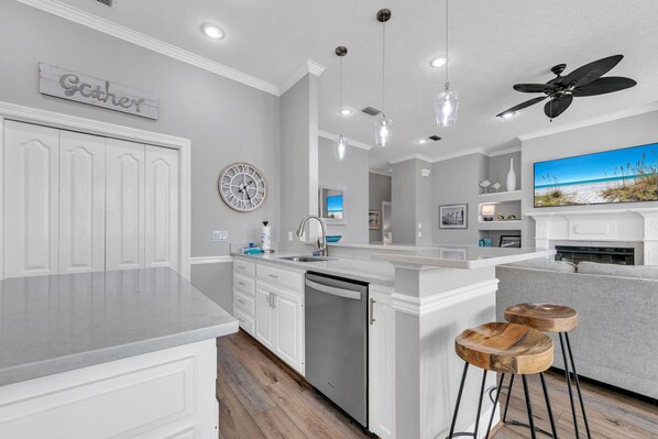 A modern kitchen with white cabinetry, a central island, pendant lighting, and a ceiling fan.