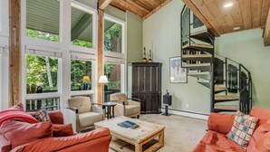 Un salón amplio con un gran ventanal, una escalera y un rincón de estar acogedor.
