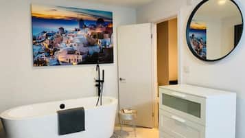 A modern bathroom with a freestanding bathtub, a large mirror, and a white vanity.