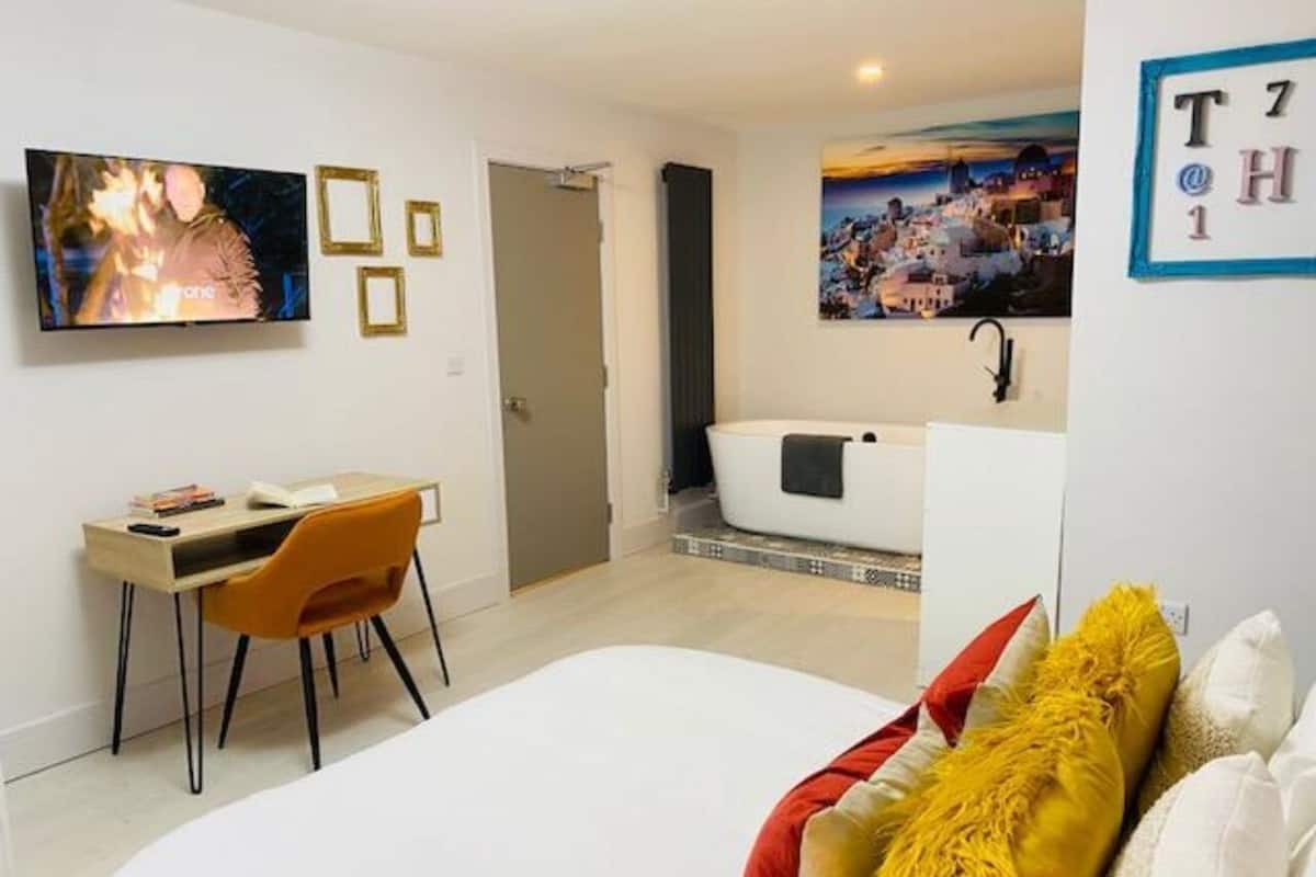 Una habitación de hotel moderna con cama, escritorio y bañera.