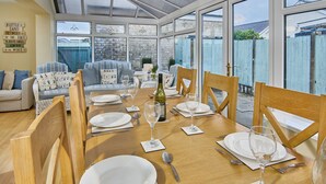 Un coin repas avec une table en bois dressée pour six personnes, entourée de chaises en bois.