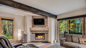 A cozy living room with a fireplace, leather seating, and large windows offering a view of the outdoors. - 🏔️Ski-in, Ski-out Condo~Hot Tub~Interlude 101🏔️ (Snowmass Village)