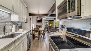 A modern kitchen with white cabinets, a stainless steel range hood, and a black stovetop. - 🏔️Ski-in, Ski-out Condo~Hot Tub~Interlude 101🏔️ (Snowmass Village)