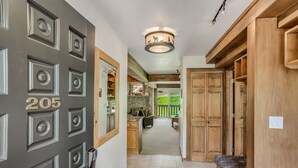 A hallway with a door labeled '205', wooden cabinets, a bench, and a stone fireplace in the background. - 🏔️Ski-In, Ski-Out Condo~Hot Tub~Interlude 205🏔️ (Snowmass Village)