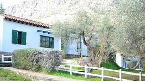 A white building with green shutters and a red-tiled roof, surrounded by greenery and a white fence. - Oca Aldeaduero Hotel (Saucelle)