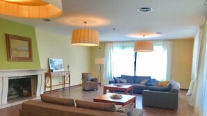 A spacious living room with a fireplace, a sofa, a coffee table, and two lamps. - Oca Aldeaduero Hotel (Saucelle)