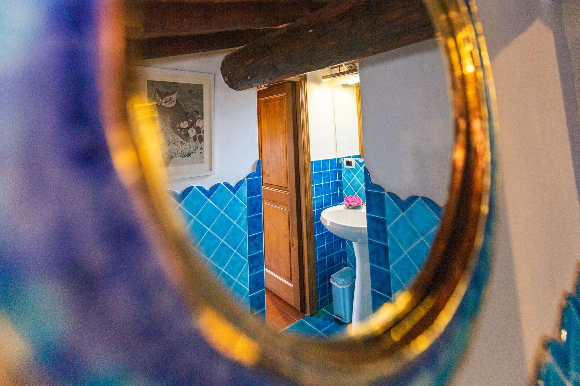 Un baño con azulejos azules, un lavabo y un espejo que refleja la habitación.