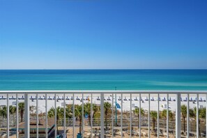 A beach view with white railings, blue umbrellas, and a clear blue sky. - The Summit 615 (Panama City Beach)