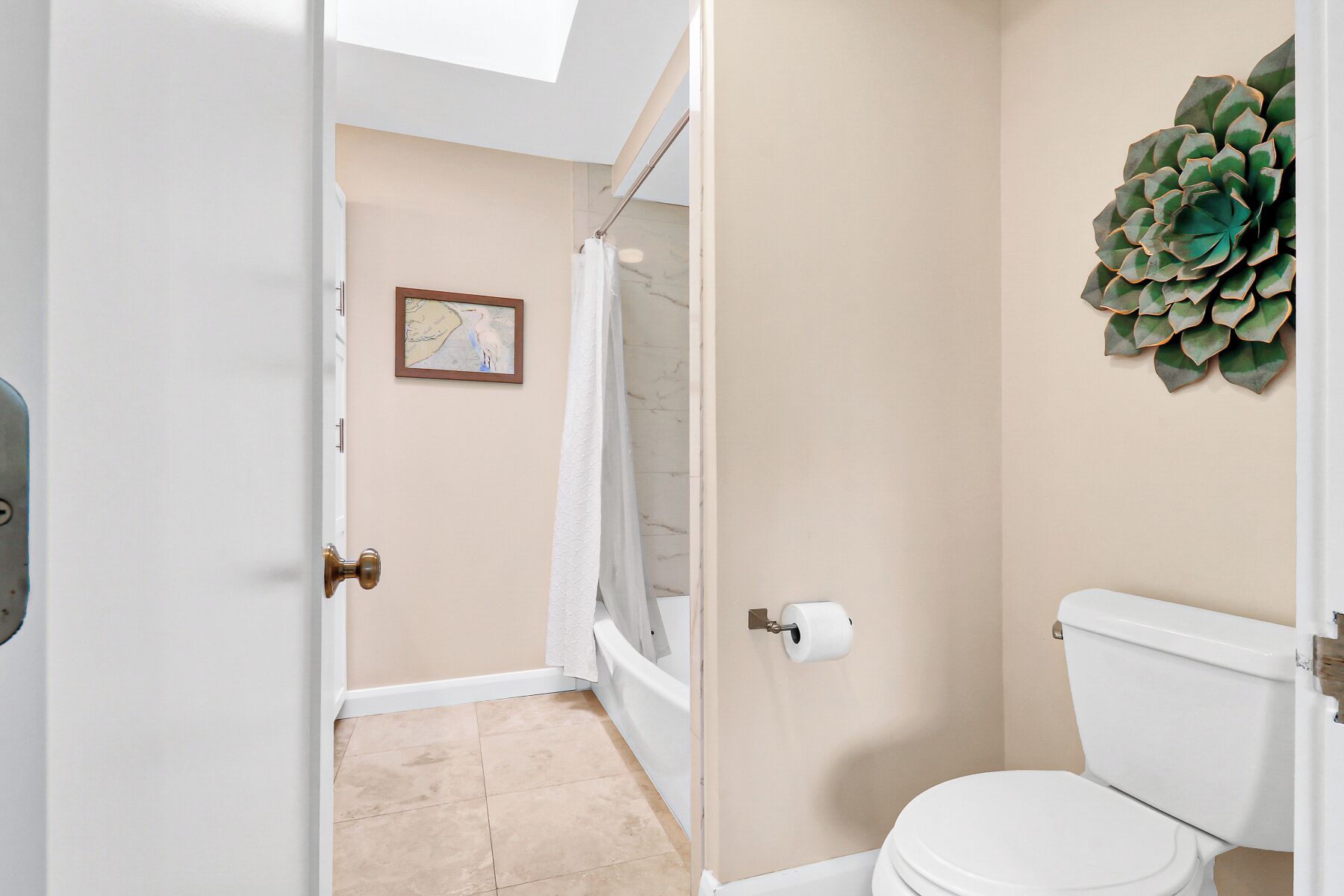 A bathroom with a toilet, shower curtain, and a wall-mounted toilet paper holder.
