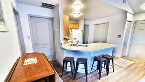 A compact kitchen with a central island, a dining table with chairs, and a small bar stool area. - Walk to Lake Rec Path! Corner Unit Close to Everything! 2 Hot Tubs (Frisco)