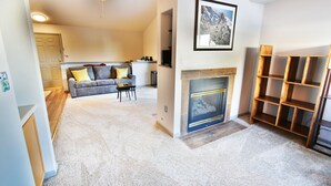 A living room with a fireplace, a sofa, and a coffee table. - Walk to Lake Rec Path! Corner Unit Close to Everything! 2 Hot Tubs (Frisco)