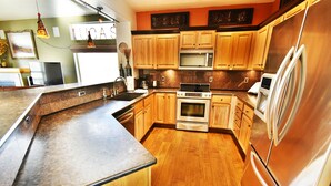 A modern kitchen with wooden cabinets, stainless steel appliances, and a granite countertop. - Big Unit, Deck! Walk to Rec Trail, Fishing. Easy Drive to Dining, Events (Silverthorne)