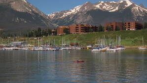 A marina with boats, a person in a kayak, and mountains in the background. - Big Unit, Deck! Walk to Rec Trail, Fishing. Easy Drive to Dining, Events (Silverthorne)