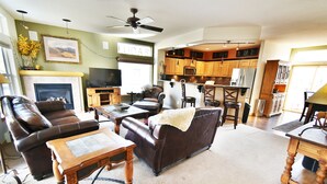 A living room with a fireplace, leather sofas, a coffee table, and a television. - Big Unit, Deck! Walk to Rec Trail, Fishing. Easy Drive to Dining, Events (Silverthorne)