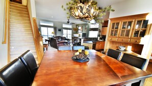 A spacious dining area with a wooden table and chairs, a chandelier, and a view of the kitchen and living room in the background. - Big Unit, Deck! Walk to Rec Trail, Fishing. Easy Drive to Dining, Events (Silverthorne)