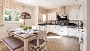 A modern kitchen with white cabinets, a dining table with chairs, and a pendant light.