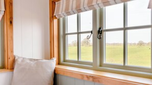 Une chambre avec une fenêtre donnant sur un champ verdoyant.